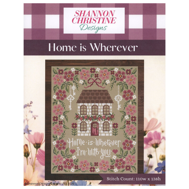front cover of the Home is Wherever cross stitch pattern featuring a white brick house surrounded by florals.
