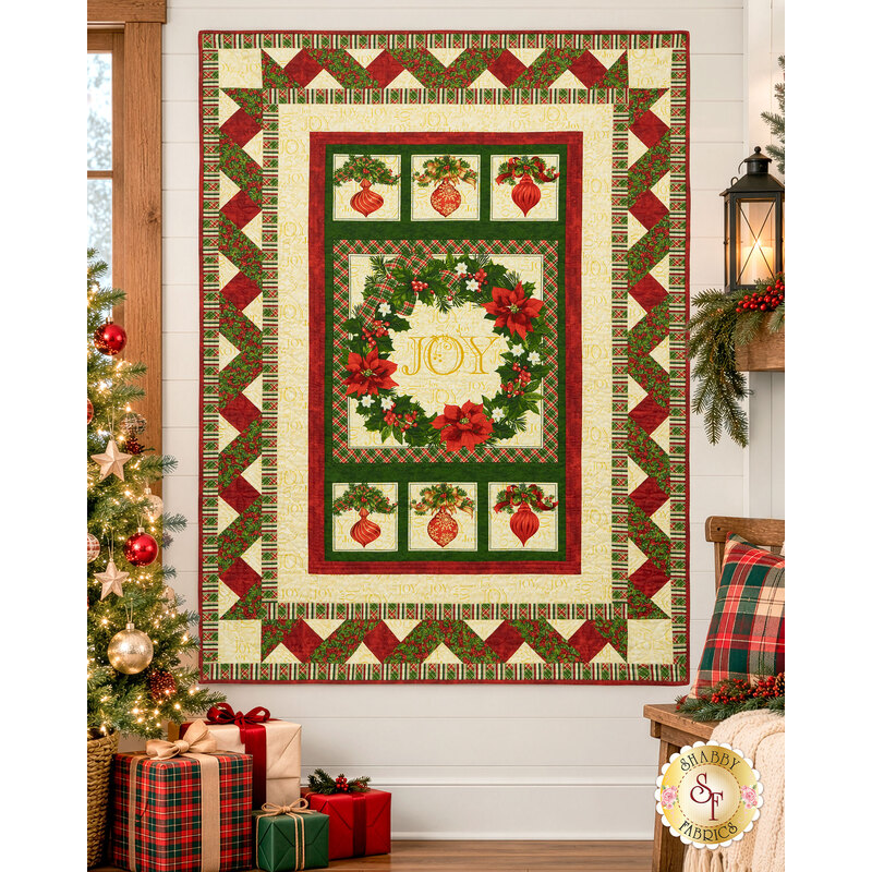 The completed Ribbon Border Panel Quilt, colored in cream, red, and green fabrics from the Deck the Halls collection by Northcott Fabrics, hung on a white shiplap wall in a cozy living room with coordinating décor.
