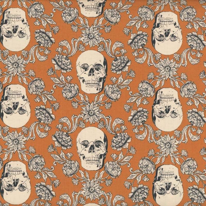 Pumpkin orange fabric with a cream-colored ornamental design of floral vines surrounding skulls.