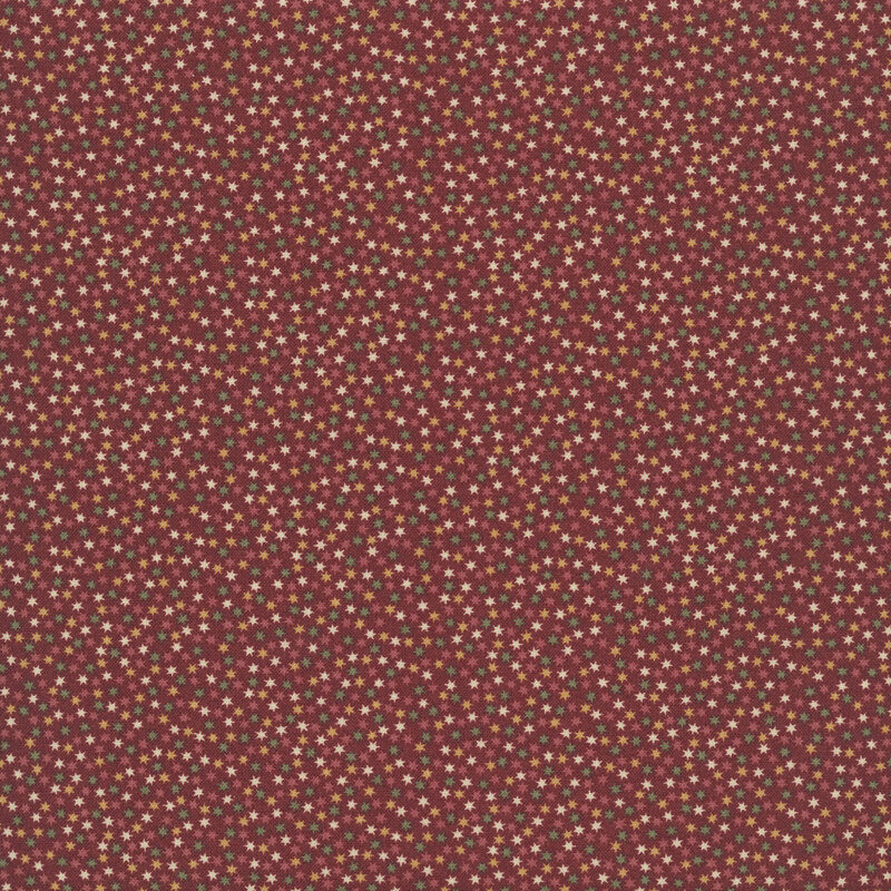 burgundy fabric packed with scattered stars in hues of gold, cream, green, and burgundy