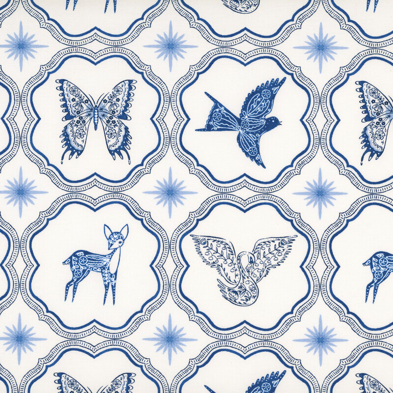 A white fabric with blue butterflies, birds, and deer inside scalloped ornamental frames separated by pale blue starbursts.