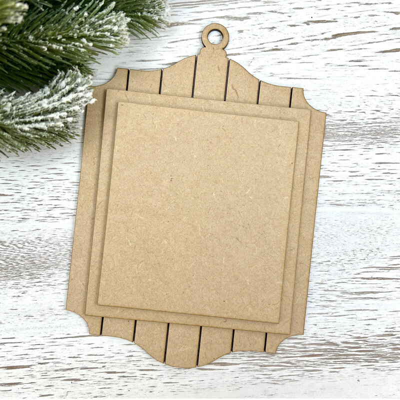 Unfinished layered MDF ornament display with a shiplap-style frame and two rectangular mounting boards for holding a small stitched piece.