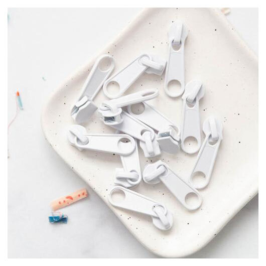 a tray of twelve size 5 white zipper pull tabs.