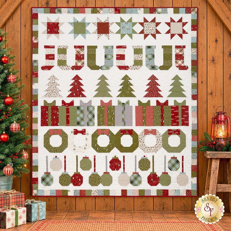 The completed Christmas Celebration Row of the Month quilt, colored in white, cream, red, green, and blue fabrics from the Chilly collection by Moda Fabrics, hung on a warm wood wall and staged with coordinating décor.