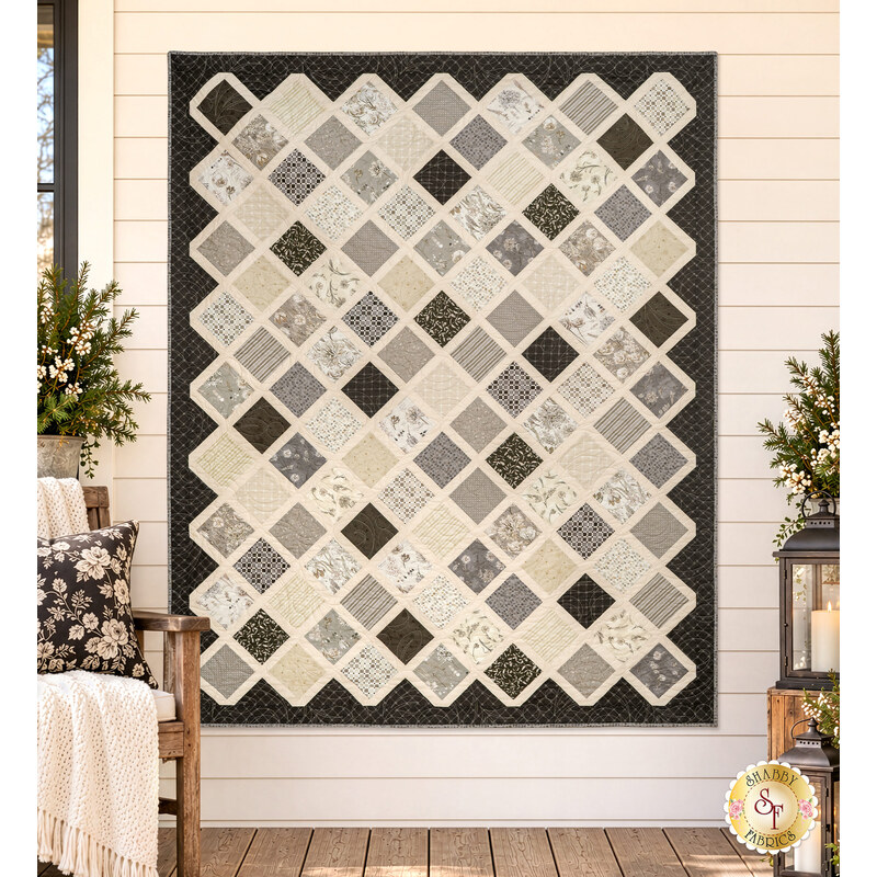 The completed Make It Scrappy Quilt, colored in elegant neutrals from the Botanical Sketchbook collection by White Owl Textiles, hung on a cream shiplap wall and staged with coordinating décor and furniture.