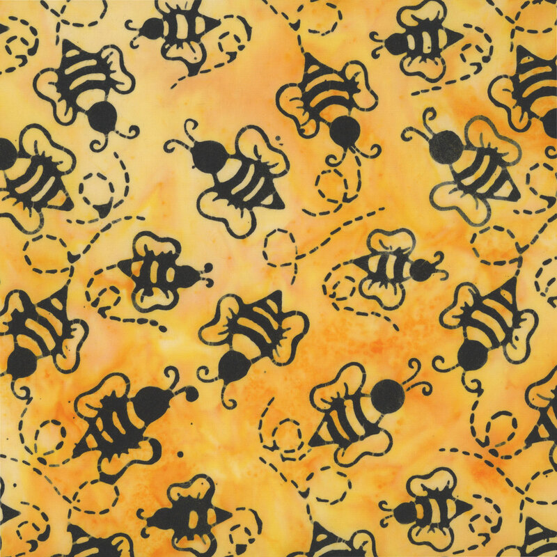 This mottled honey yellow batik fabric features tossed black bumble bees. 