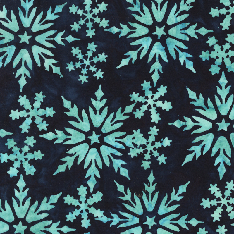 A navy batik fabric with large and small aqua snowflakes in assorted intricate shapes.