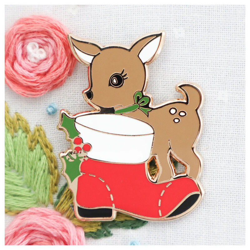 The Reindeer Wishes Needle Minder featuring a baby reindeer with a red boot, displayed on a hand embroidery project.