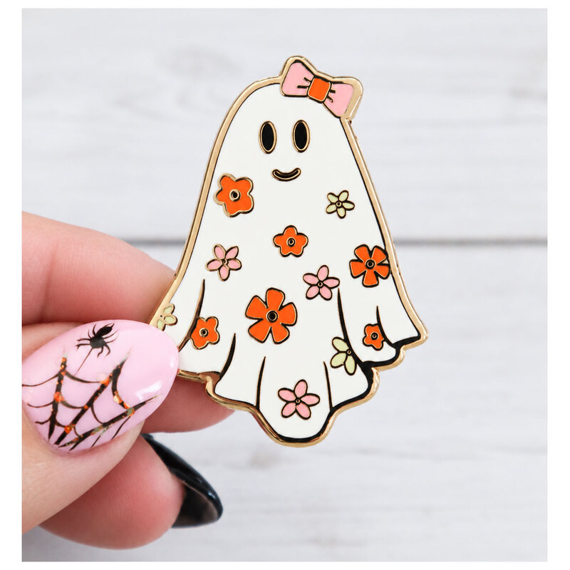 a hand holding the Groovy Ghost needle minder featuring a white ghost with orange and pink florals and a pink bow.