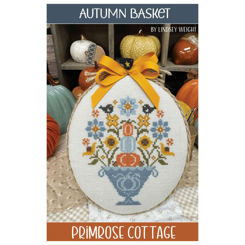 The front cover of the Autumn Basket pattern showcasing the finished project featuring fall florals, pumpkins, and black birds.