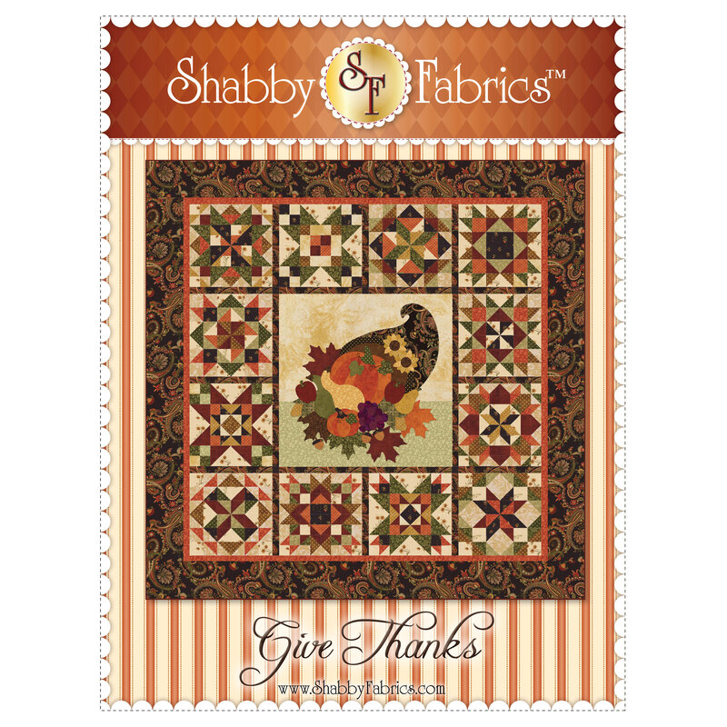 The finished Give Thanks quilt with an applique cornucopia in the center, surrounded by 12 pieced sampler blocks.