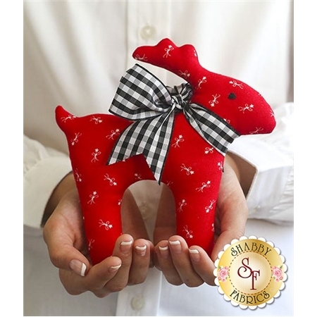 A person holding a red fabric reindeer ornament with a black and white checked bow.