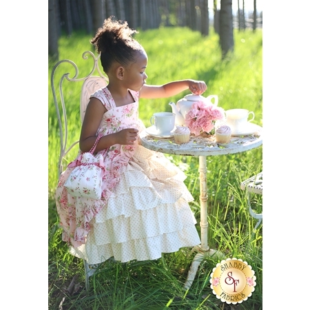 A little girl with a tea set wearing the Tea Party Dress.