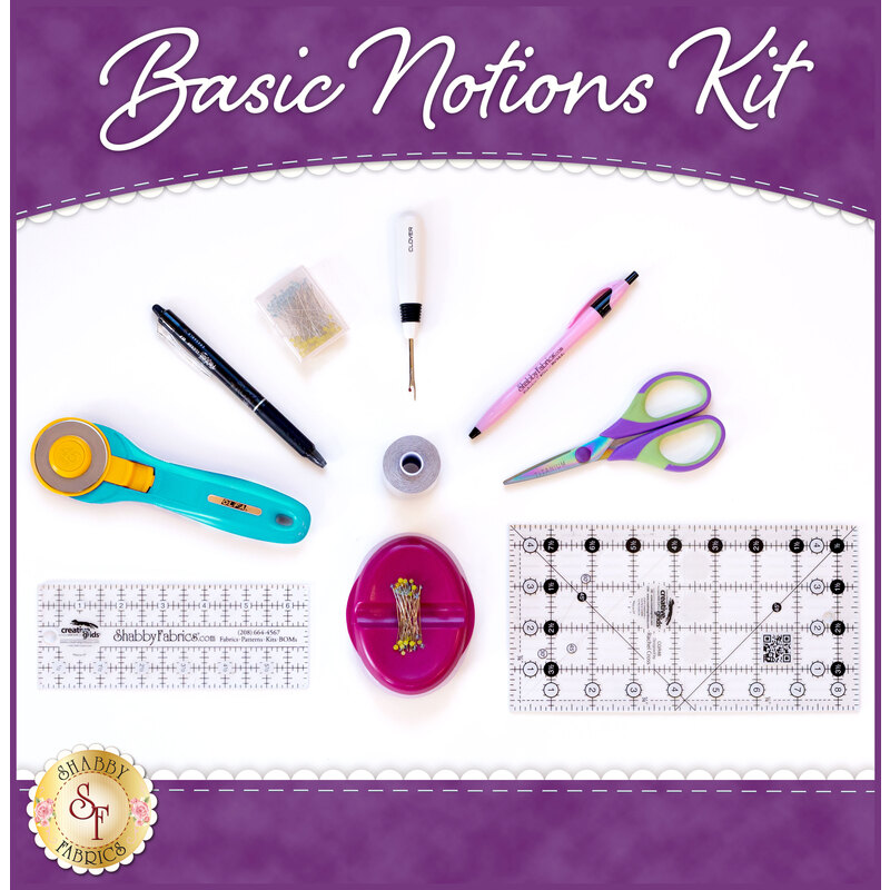 A flat lay of various sewing tools arranged on a white background. Items include a rotary cutter, a seam ripper, a pen, scissors, fabric clips, two rulers with measurement markings, and a small container for pins. The top of the image has the text Basic Notions Kit and the bottom features a logo.