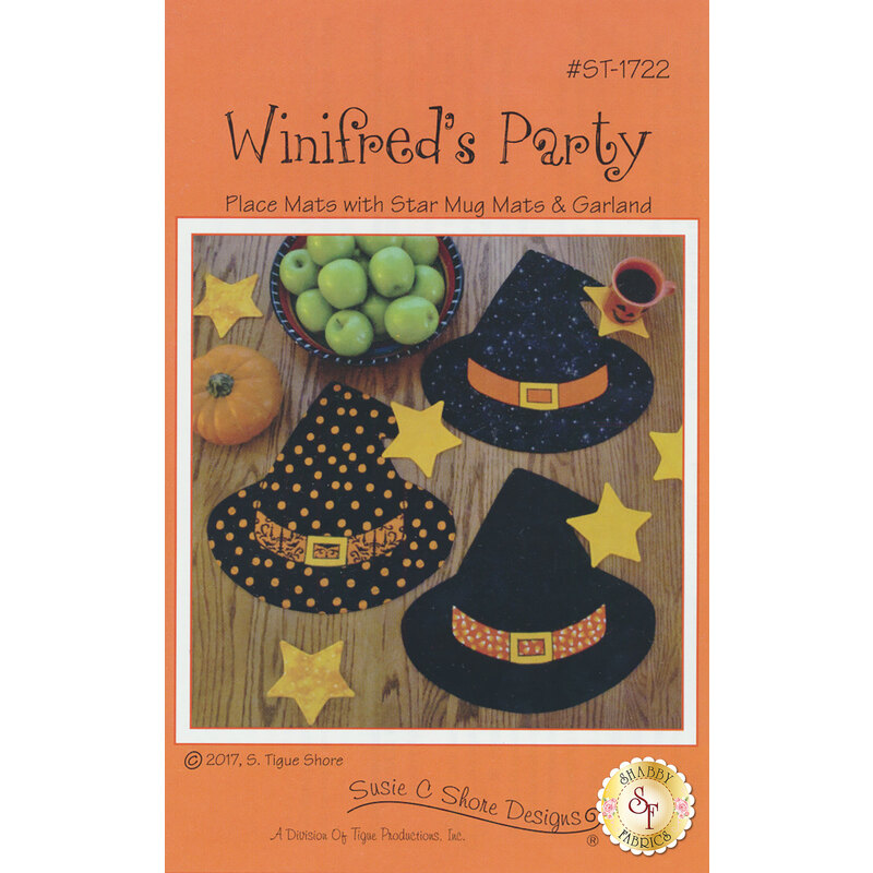 A bright orange cover with the text Winifred's Party featuring images of three witch hats in black and orange patterns. There are yellow stars around the hats and a small pumpkin next to a bowl of green apples. The design emphasizes decorative place mats and garland for a festive occasion.