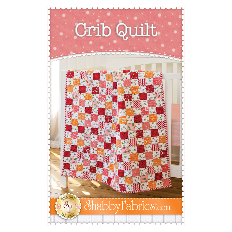 Front cover of Crib Quilt pattern, with patchwork quilt draped over edge of crib