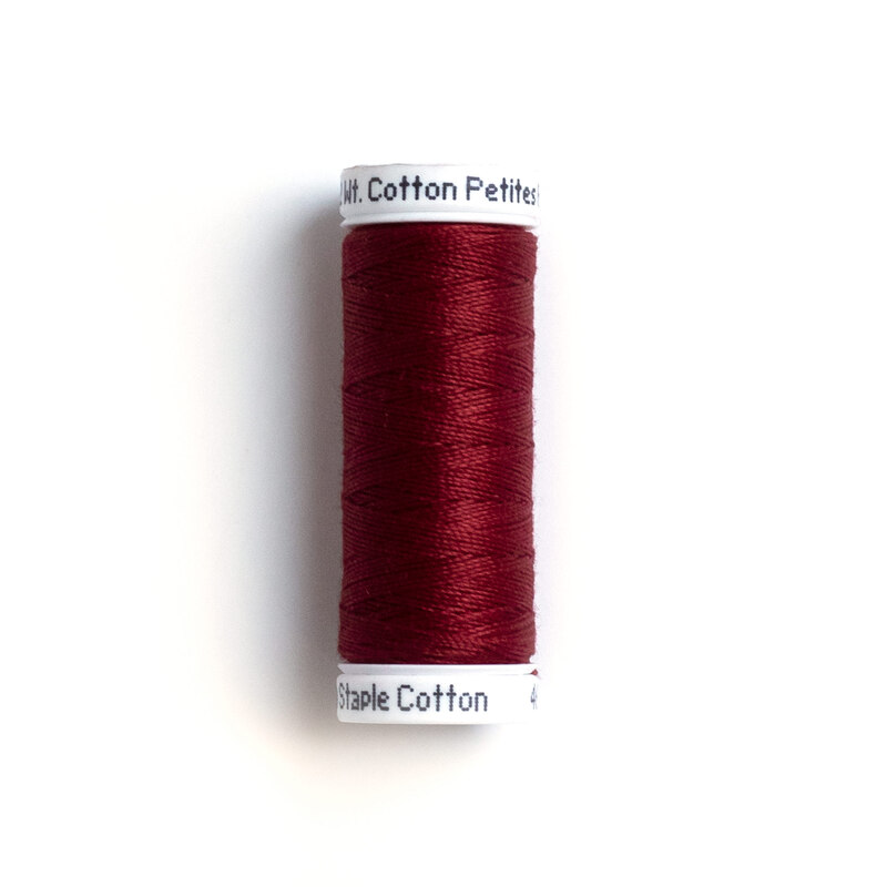 Red cotton thread on a white spool, labeled Cotton Petites, displayed upright against a white background.