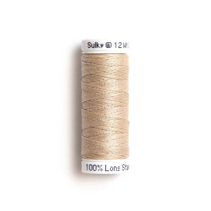 A spool of light beige sewing thread with the brand name Sulky and a label indicating it is 100% long staple cotton.