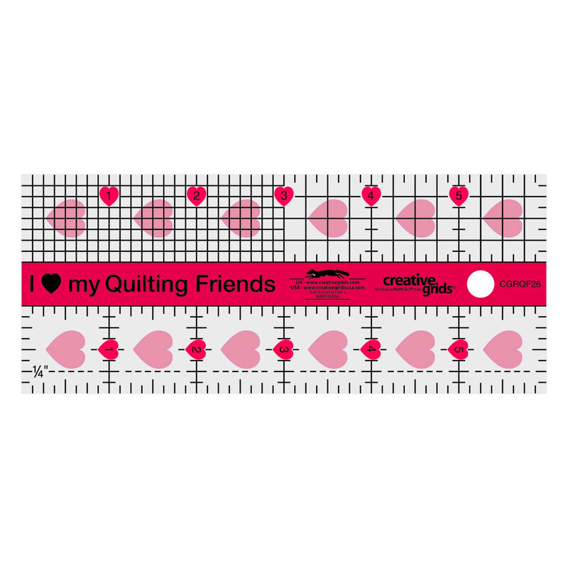 A clear acrylic quilting ruler with a grid pattern, hearts, and the phrase 