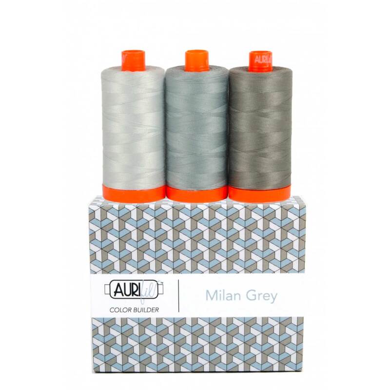 A spool of light, medium, and dark gray thread on an Aurifil Colorbuilder box