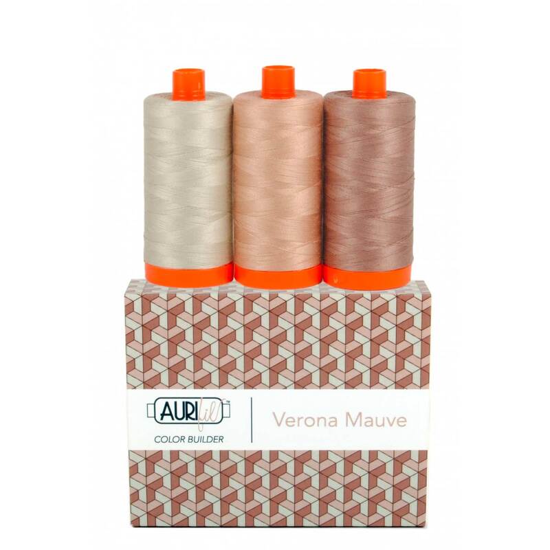 A spool of light, medium, and dark mauve thread on an Aurifil Colorbuilder box